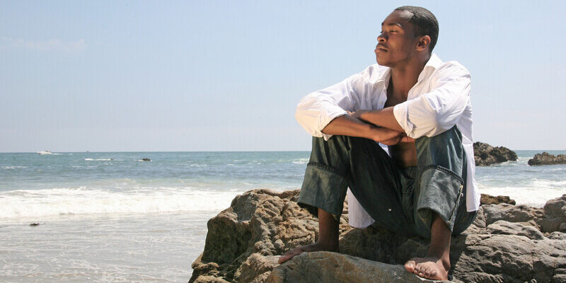 Man Sitting On. Rock At The Beach, Thinking