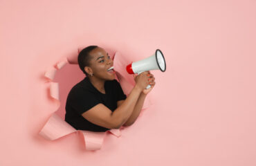 Woman Using Megaphone Through Hole In Wall