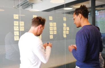 Two Men Mapping Out Strategy and Tactics On White Board With Post It Notes