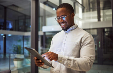 Business man using tablet in office building and smiling