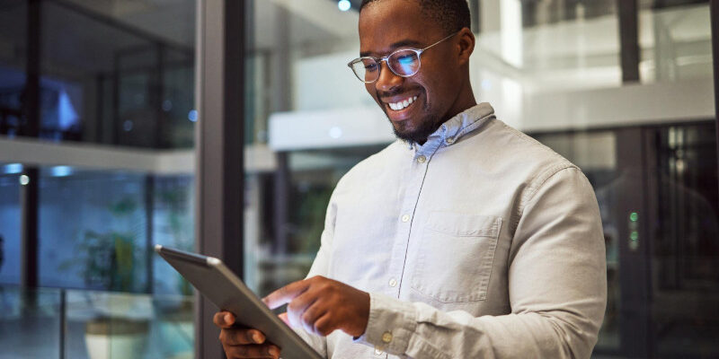 Business man using tablet in office building and smiling