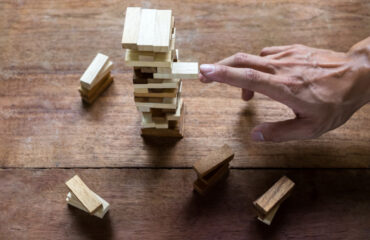 Hand making risky play by removing a block in Jenga game