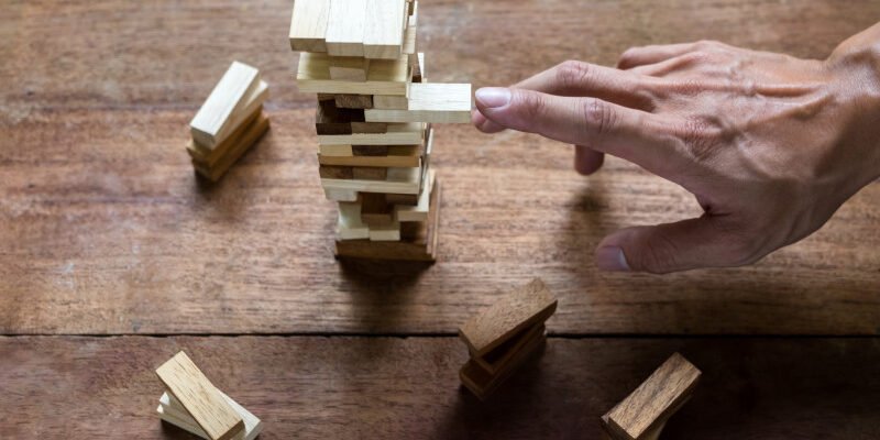 Hand making risky play by removing a block in Jenga game
