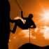 Silhouette of man climbing a mountain against sunny background