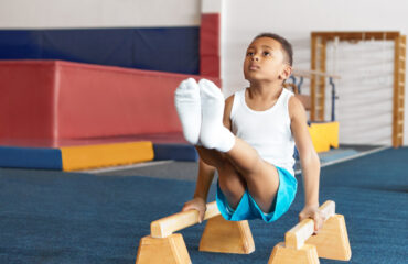 Self determined disciplined little sportsman doing balancing act