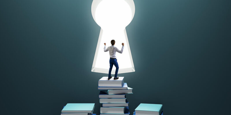 Education and knowledge concept with happy man reaching a keyhole by stepping on books