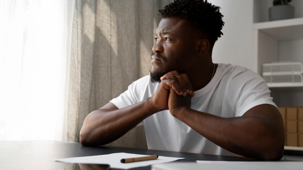 Man contemplating writing on piece of paper with pen