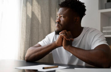 Man contemplating writing on piece of paper with pen