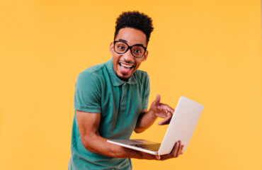 Excited young man pointing at laptop in hand
