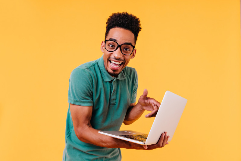 Excited young man pointing at laptop in hand