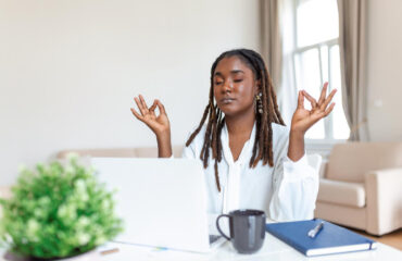 Calm female executive meditating taking break at work for mental balance