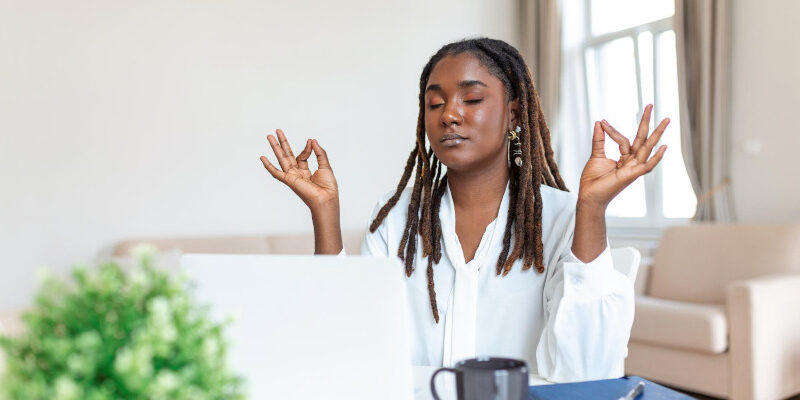 Calm female executive meditating taking break at work for mental balance