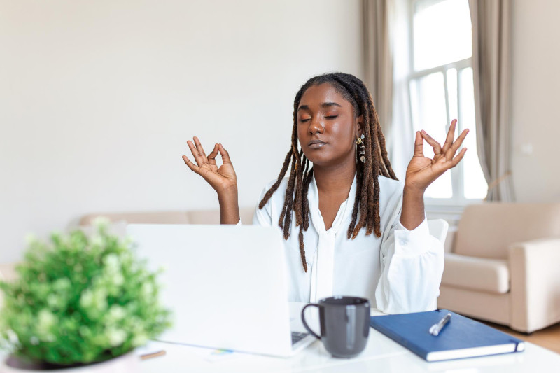 Calm female executive meditating taking break at work for mental balance