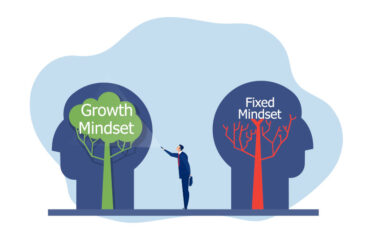 Businessman holding flashlight to growth mindset head adjacent to a stagnant head concept