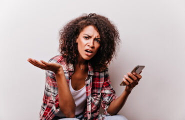 Frustrated young woman holding smartphone