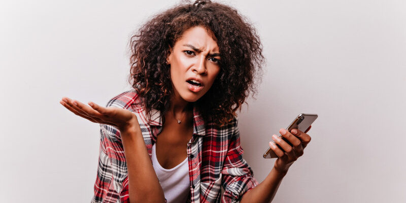 Frustrated young woman holding smartphone