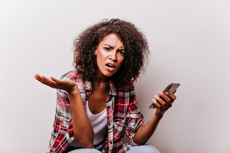 Frustrated young woman holding smartphone