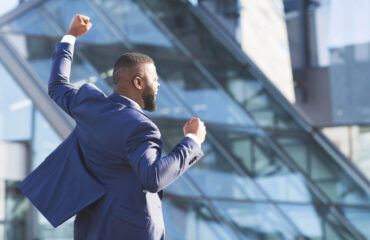 Man shaking fists rejoicing business success outdoors