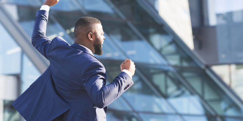 Man shaking fists rejoicing business success outdoors