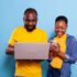 Happy man and woman using laptop computer and smartphone in studio