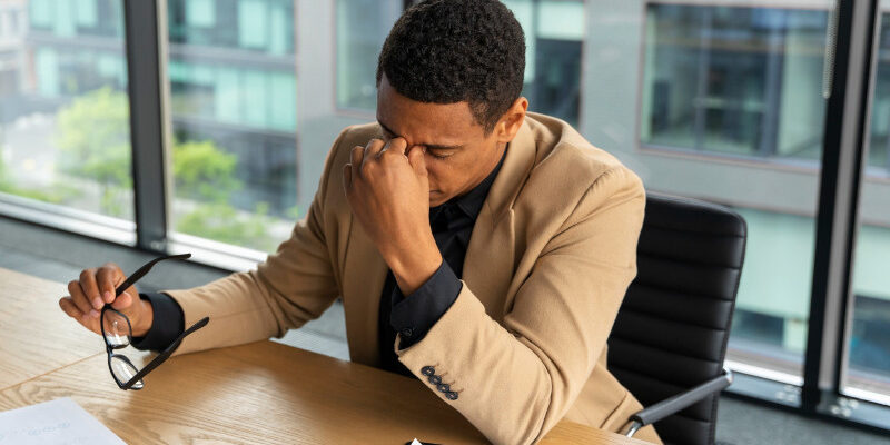 Man sitting at a desk in despair with documents in front of him