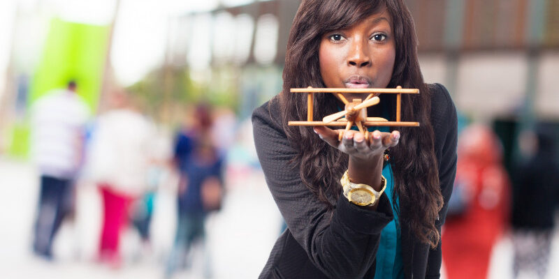 Woman with a wooden plane in her hand, blowing at it