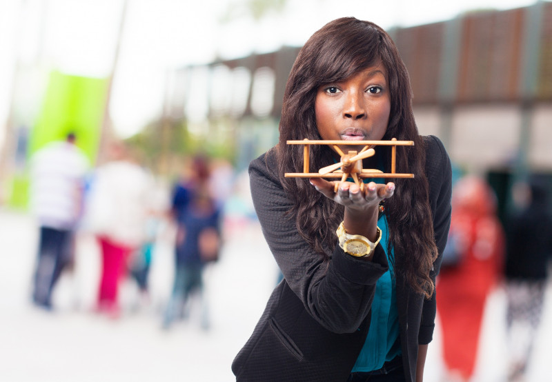 Woman with a wooden plane in her hand, blowing at it