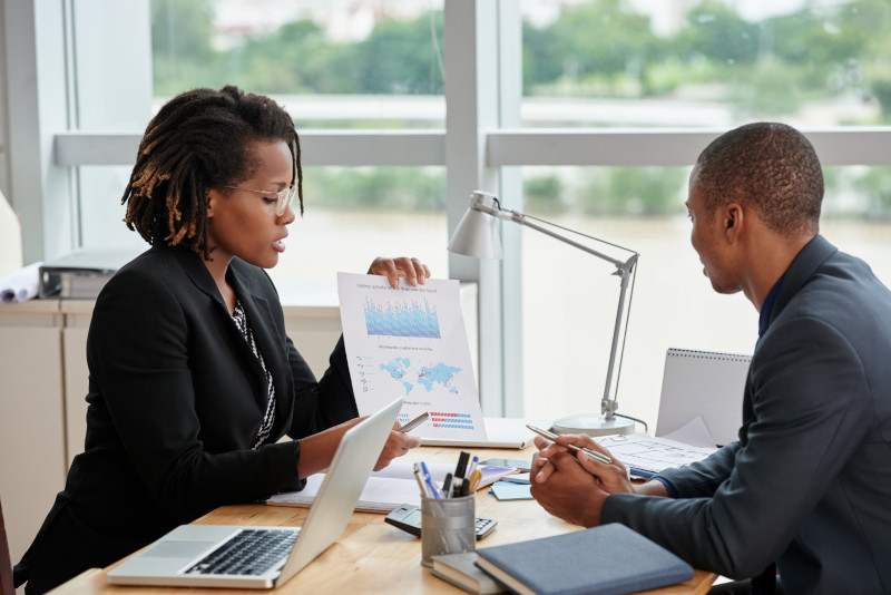 Businesswoman showing analytical charts to her male coworker