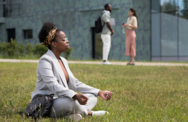 Woman sitting crosslegged on the lawn, relaxing in meditation pose