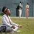 Woman sitting crosslegged on the lawn, relaxing in meditation pose