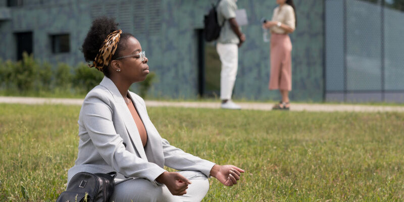 Woman sitting crosslegged on the lawn, relaxing in meditation pose