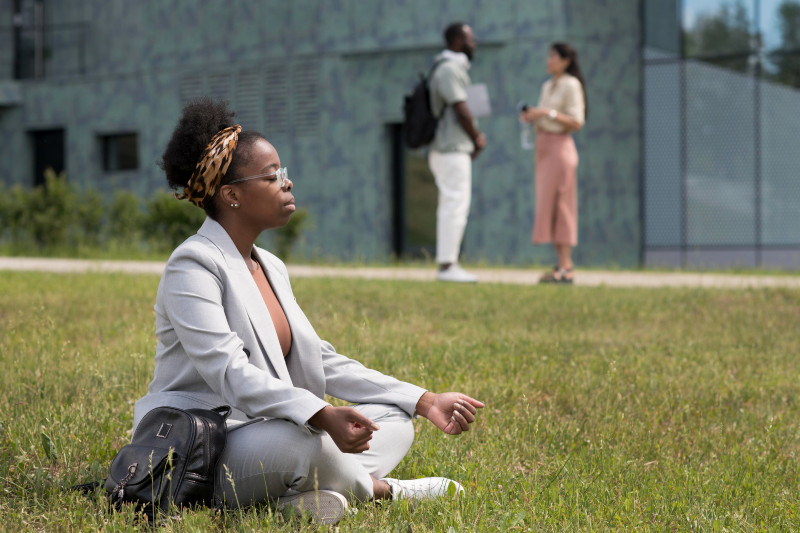 Woman sitting crosslegged on the lawn, relaxing in meditation pose