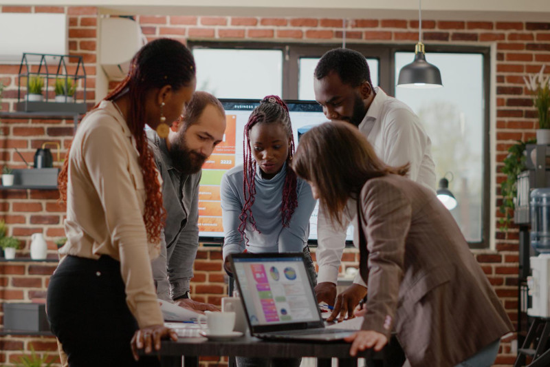 Team of colleagues analyzing charts on documents to plan customer retention project