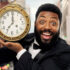 Happy exited bearded man in black suit holding golden clock