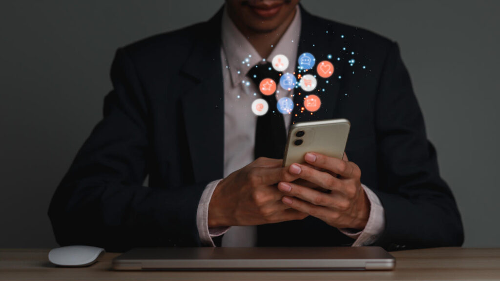 Concept of business man in a suit hlding a smartphone with a bubble of icons floating around it