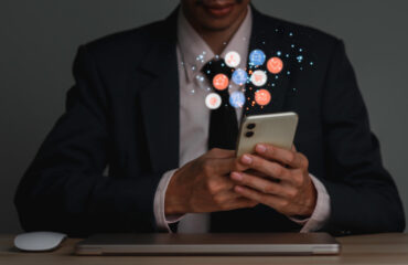 Concept of business man in a suit hlding a smartphone with a bubble of icons floating around it