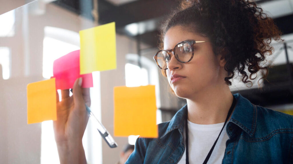 Young business woman with post its on a glass window