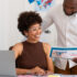 people in travel agency office looking at laptop and documents