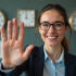 A business professional woman smiling and gesturing 'stop' with a raised hand against a backdrop of antique clocks