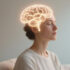 A woman sitting calmly with eyes closed, glowing neural pathways inside the brain illustrated with soft light