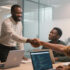 Business owner shaking hands with a developer in an office with other developers