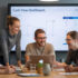 A startup team gathered around a large screen displaying a Cash Flow Dashboard, smiling as they plan budgets together