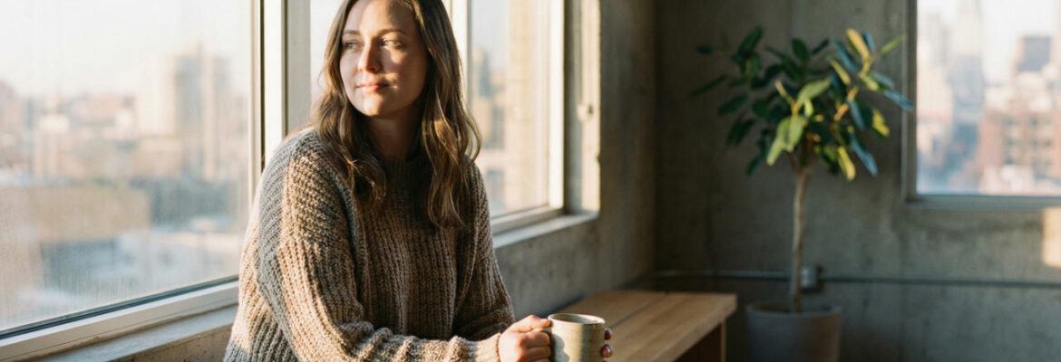 Woman Sitting on Bench at Sunrise Holding Coffee Mug